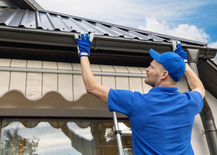 man installing house roof rain gutter system